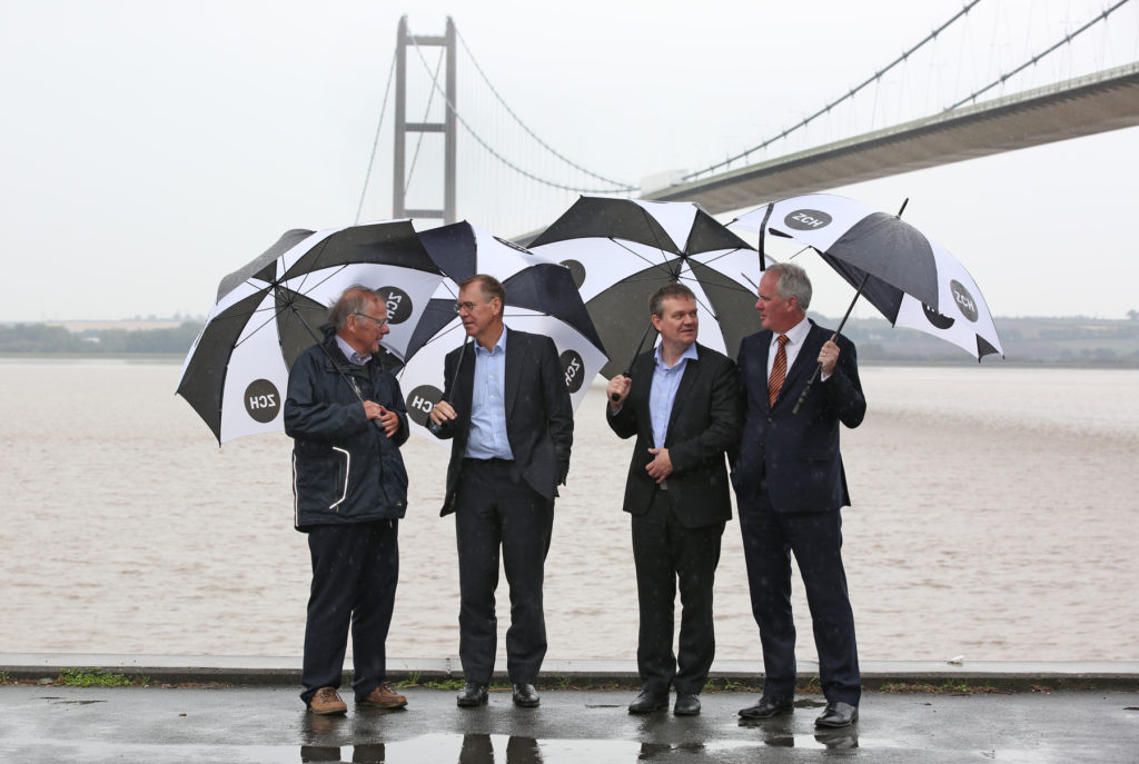Zero Carbon Humber partners at launch event with umbrellas pictured under the Humber Bridge
